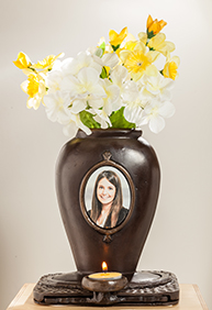 A vase with flowers in it and a picture of a woman.